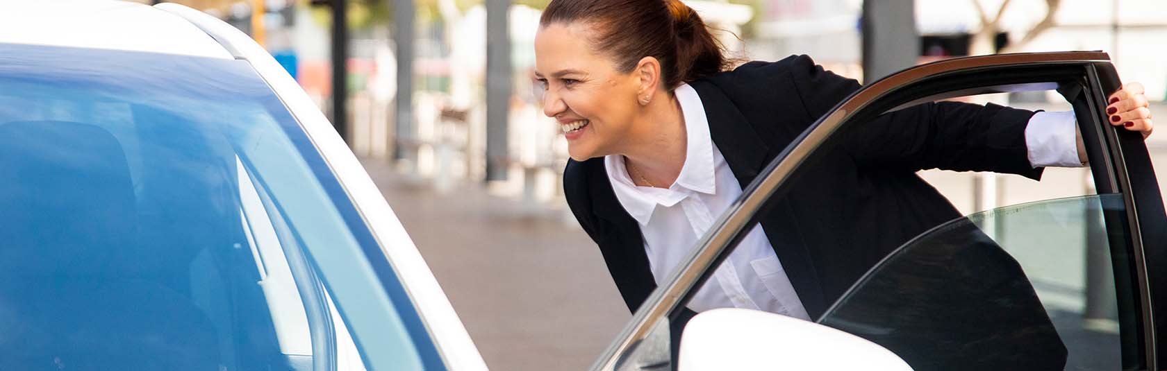 Woman smiling and entering a white car